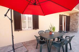 费拉约港Villetta Capo Bianco - Goelba的一张桌子和椅子,配有红色雨伞
