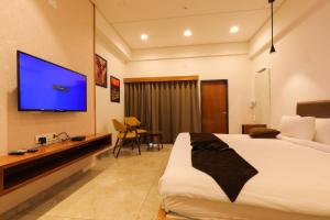PālanpurCLUB HEAVEN PALANPUR的配有一张床和一台平面电视的酒店客房