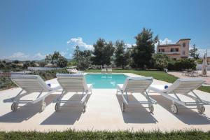 莫诺波利Villa Dyria exclusive swimming pool的四把躺椅和一个游泳池