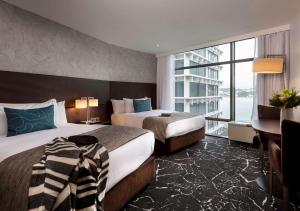惠灵顿惠灵顿雷吉斯酒店的酒店客房设有两张床、一张书桌和一个窗户。