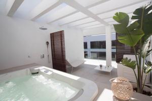 埃斯普霍斯Sa Pedrera Suites & Spa的白色的浴室设有浴缸和植物