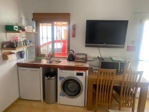 ArboleasCasa Sol y Luna的一间带洗衣机的厨房和一台墙上的电视
