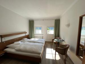 阿斯曼斯豪森舍恩酒店的一间卧室配有一张床、一张桌子和一把椅子