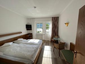 阿斯曼斯豪森舍恩酒店的一间卧室配有一张床、一张桌子和一个窗户。