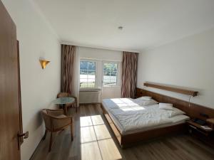 阿斯曼斯豪森舍恩酒店的一间卧室配有一张床、一张桌子和一个窗户。