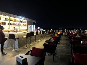 ElwaLifestyle Luxury Hotel and Residence的一间晚上设有酒吧的餐厅,酒吧配有桌椅