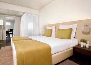 特罗亚Aqualuz Troia Rio by The Editory的卧室配有一张带黄色枕头的大型白色床。