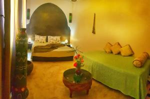 马拉喀什卡尔曼达摩洛哥传统庭院旅馆的一间卧室配有两张床和一张带绿床的桌子。