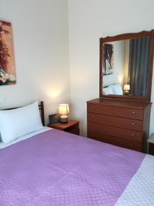 Néa KhilíΔιαμέρισμα σε πολυκατοικία的一间卧室配有一张紫色的床和镜子