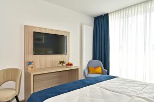 韦德尔HotelHafenWedel的一间卧室配有一张床、一台电视和一把椅子