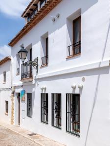 阿尔啼Hostal Perla Blanca Altea的白色的建筑,设有黑窗和街道