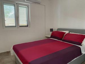 克拉西奇Villa Miran Boka Bay的一间卧室配有一张大床,提供红色和紫色床单