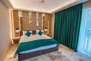 比斯特里察Hotel Codrişor的一间卧室配有一张带绿色窗帘的大床
