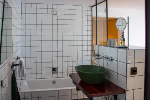 斯鲁伊斯De 6 Linden Boutique Hotel的浴室在浴缸旁的桌子上摆放着一个绿色碗