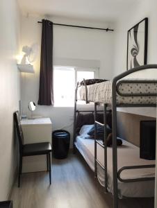 巴塞罗那Vilapicina Hostal的卧室配有双层床、书桌和椅子