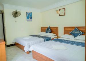 吉婆岛Long Thành Motel的一间设有两张床的客房和墙上的时钟