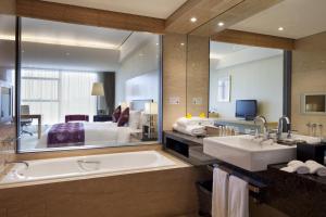 天津天津滨海圣光皇冠假日酒店的一间带浴缸和大镜子的浴室