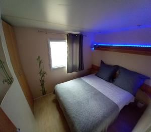 萨尔拉拉卡内达Mobile home au camping les Tilleuls du Caminel的一间小卧室,配有一张蓝色的灯光床