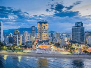 芽庄MySea Panorama Nha Trang Superview Apartments的城市天际线,晚上有海滩