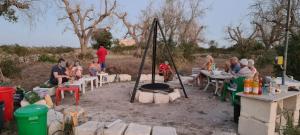 库特罗菲安诺Camping Terreno-Ro-Bi-Li的一群人坐在火坑周围的桌子旁