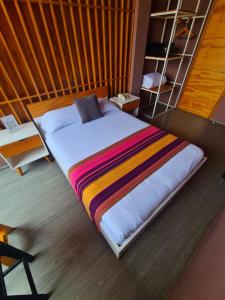 图斯特拉古铁雷斯Hotel Momotus的一张床上有五颜六色的毯子,放在房间里