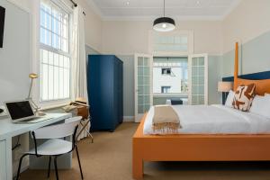 开普敦Neighbourgood Hill Suites的一间卧室配有一张床和一张带笔记本电脑的书桌