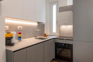 米兰BnButler - Sebenico, 28 - Nuovissimo Appartamento in Isola的厨房配有白色橱柜、水槽和窗户。
