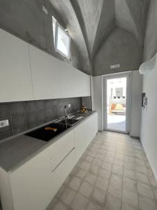 马奥莱Mana House2的厨房配有白色橱柜、水槽和窗户。