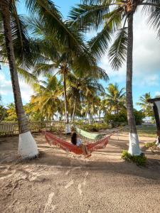 曼格斯塞克Pousada o Forte的躺在棕榈树海滩上的吊床上的人