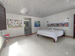 格兰德岛Isla Grande Eco-Hostal的卧室配有一张床,墙上挂有绘画作品