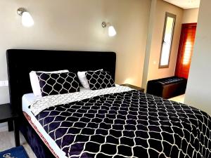 诺阿瑟Short Stay Apartment aéroport casablanca的卧室配有黑色和白色的床和2个枕头