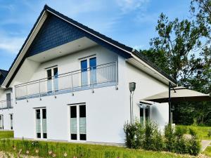 格罗斯内默罗Seeglück 2 am Tollensesee的蓝色屋顶的白色房子