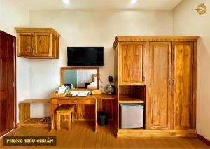 Tri TônRồng Vàng Resort的客房设有木桌和电视。