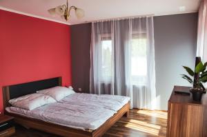 福纽德Butik Apartmanház的一间拥有红色墙壁的卧室和一张位于客房内的床