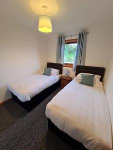 洛赫吉尔普黑德Kings Reach - Crinan Cottage的一间卧室设有两张床和窗户。