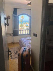 索维拉Essaouira Beach Hostel的一间设有床、窗户和行李箱的房间