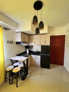 塔里萨伊Cozy almond drive condo in cebu的厨房配有黑色冰箱和带凳子的桌子