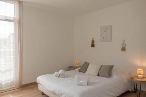 Saint-Jean-de-la-RuelleLe Gambetta *T3* + Parking的一张白色的床,坐在一个窗户的房间