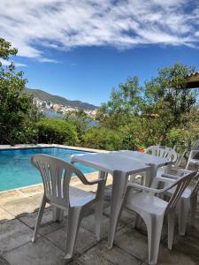 维拉卡洛斯帕兹casa con vista y bajada al lago的游泳池旁的白色桌椅