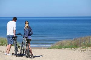 波讷地区圣朱利安Gite mahiou的一名男子和一名女子,用自行车站在海滩上