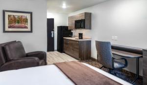 East MolineMy Place Hotel-East Moline/Quad Cities, IL的酒店客房带一张床、一张桌子和椅子