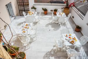 安德罗斯Archontiko Eleni Hotel的庭院配有白色桌椅和食物