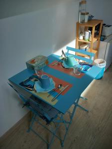 ChâtresLa Bord de Mer (au Portail Bleu)的一张带椅子的蓝色桌子和盘子