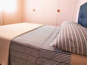 甘迪亚海滩Apartamento Sabor del Mar solo Familias的床上有条纹毯子