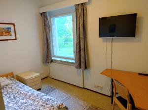 MonolaHostel Vanha Koulu的一间卧室配有一张床、一台电视和一个窗口