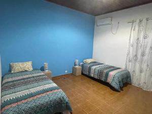 圣多美Tropical Paradise的一间卧室设有两张床和蓝色的墙壁