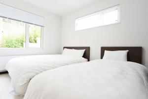 札幌Sapporo - House - Vacation STAY 14578的白色卧室设有两张床,配有两个窗户