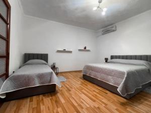 地拉那Vila Kodra的白色客房的两张床,铺有木地板