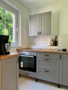 雷姆沙伊德Sali - R1 - Apartmenthaus, WLAN, TV的厨房配有白色橱柜和黑烤箱。