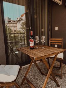 布拉迪斯拉发Elegant Escape apartment I - City Centre的木桌旁的一瓶葡萄酒和两杯酒